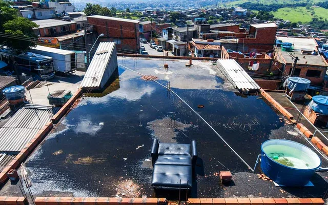 Imagem de laje de casa com água parada e caixa d'água aberta