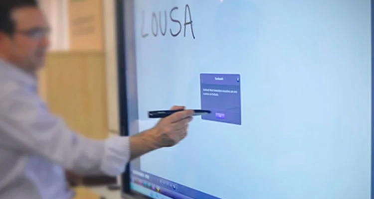 Imagem de homem utilizando a lousa digital em sala de aula