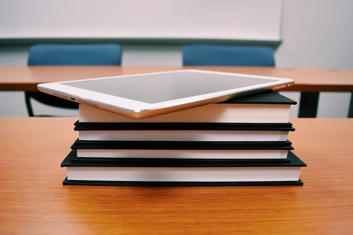 Imagem de tablet em cima de pilha de livros em cima de mesa na sala de aula